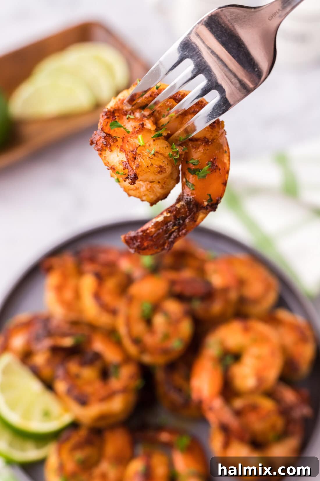 A single spicy shrimp on a fork, ready to be eaten.