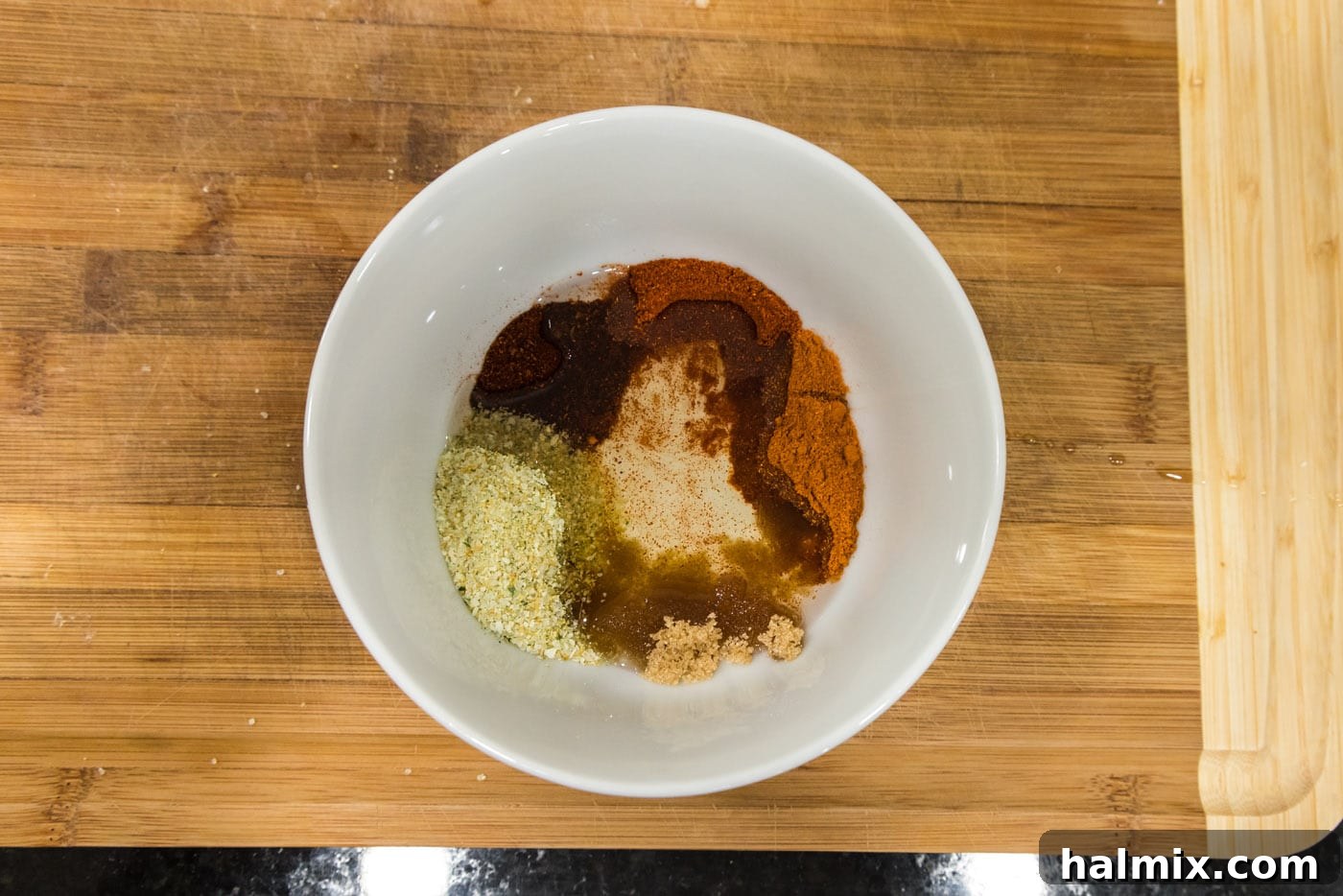 Olive oil with seasonings in a bowl, showing the initial mixing step.