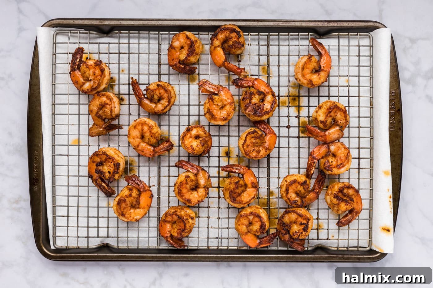 Cooked spicy shrimp resting on a wire rack, allowing excess moisture to drain.