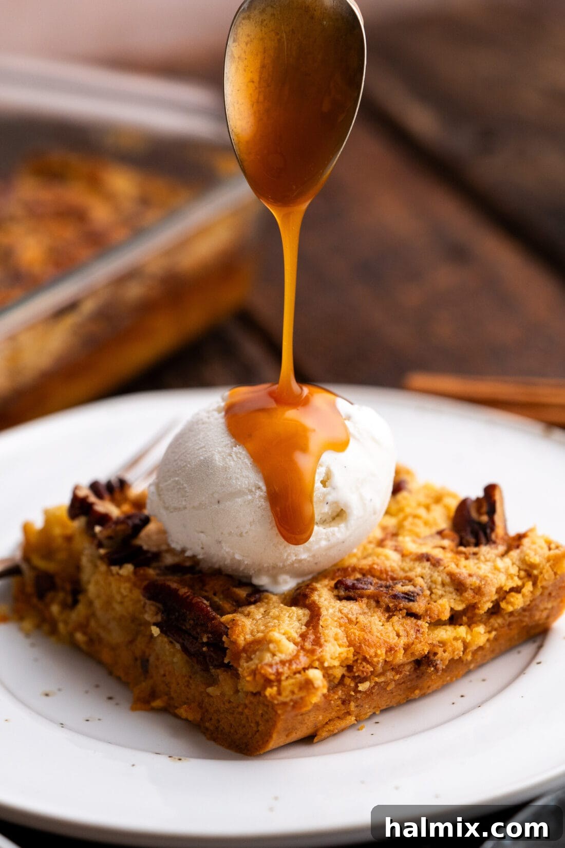 Caramel sauce being drizzled over Pumpkin Dump Cake topped with ice cream