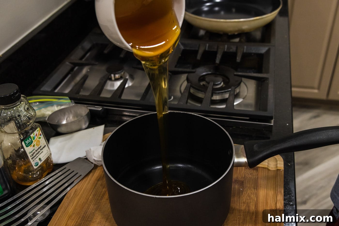 Pouring honey into a saucepan with other glaze ingredients.