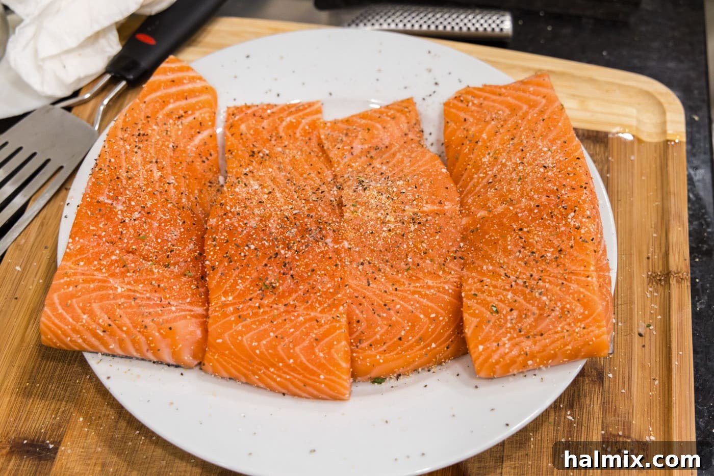 Seasoned salmon fillets on a plate, ready for cooking.