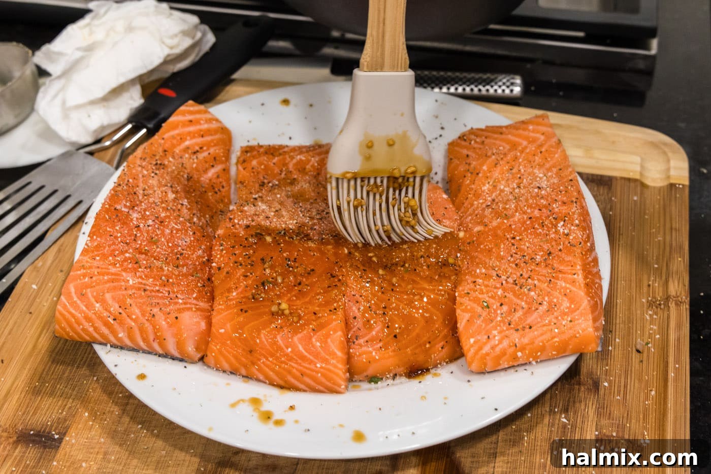 Brushing honey garlic glaze over salmon fillets in a skillet.