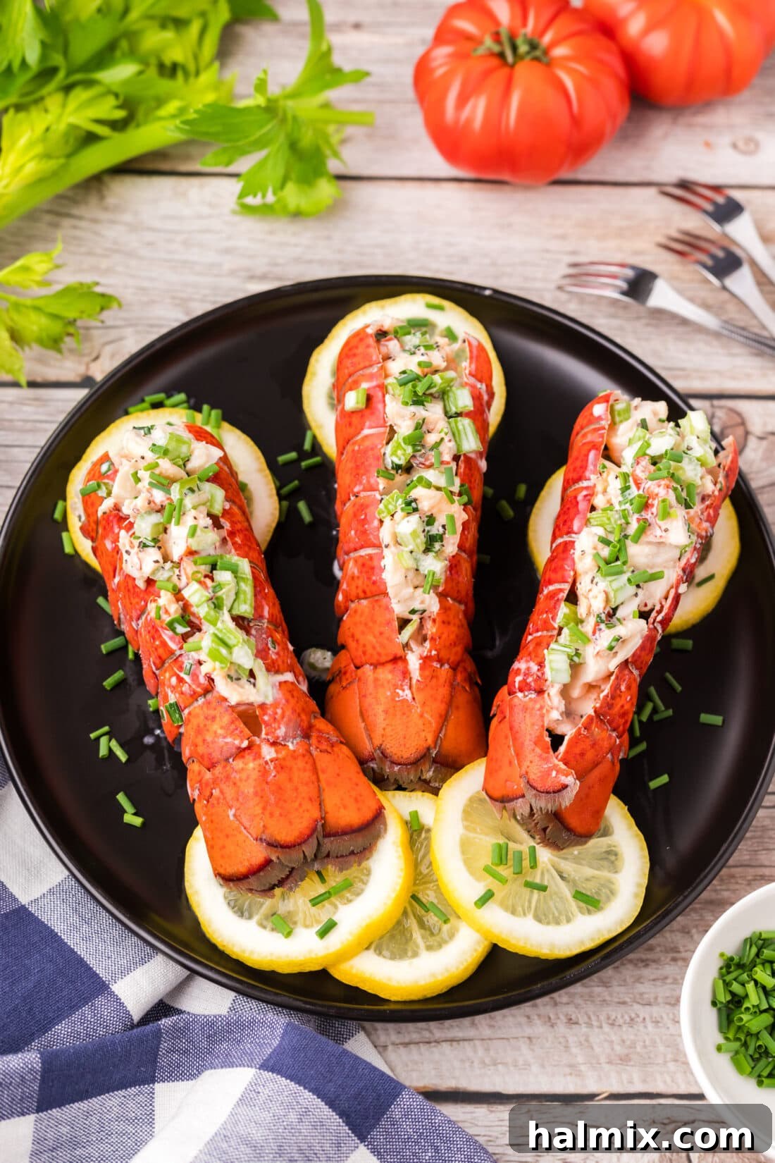 An inviting overhead view of lobster salad elegantly served in hollowed-out lobster tails on a rustic wooden board, garnished with fresh herbs and lemon wedges.