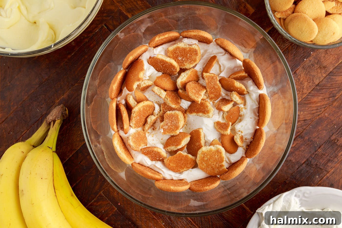 Crushed Nilla wafers added on top of a whipped cream layer in a trifle bowl.