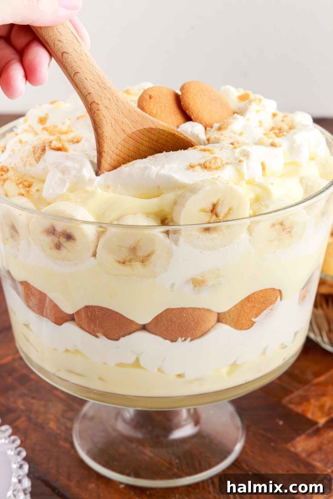 Serving spoon digging into a layered Banana Trifle dessert.