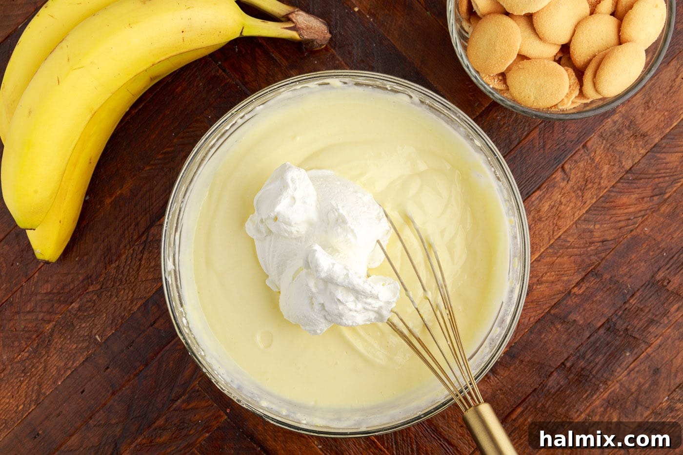 Folding a dollop of whipped cream into the cream cheese pudding mixture.