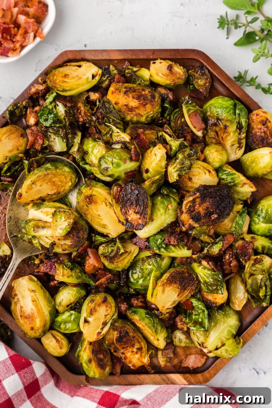 Close up photo of Brussels Sprouts with Bacon, Shallots and Candied Pecans on a wooden platter, showcasing crispy bacon and glazed pecans