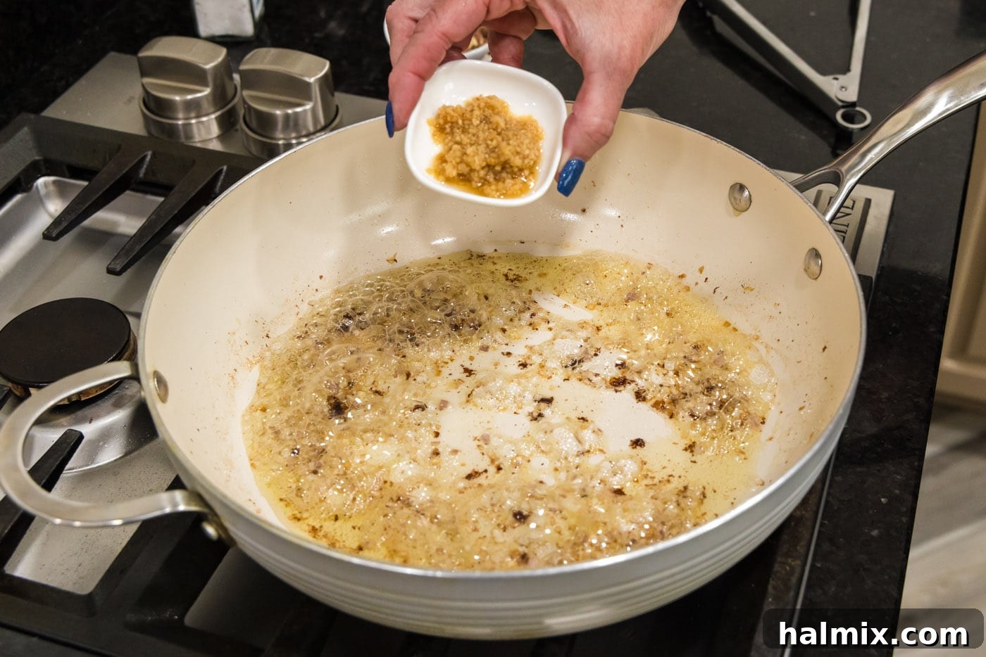 adding garlic to skillet with shallots and oil, enhancing the aroma