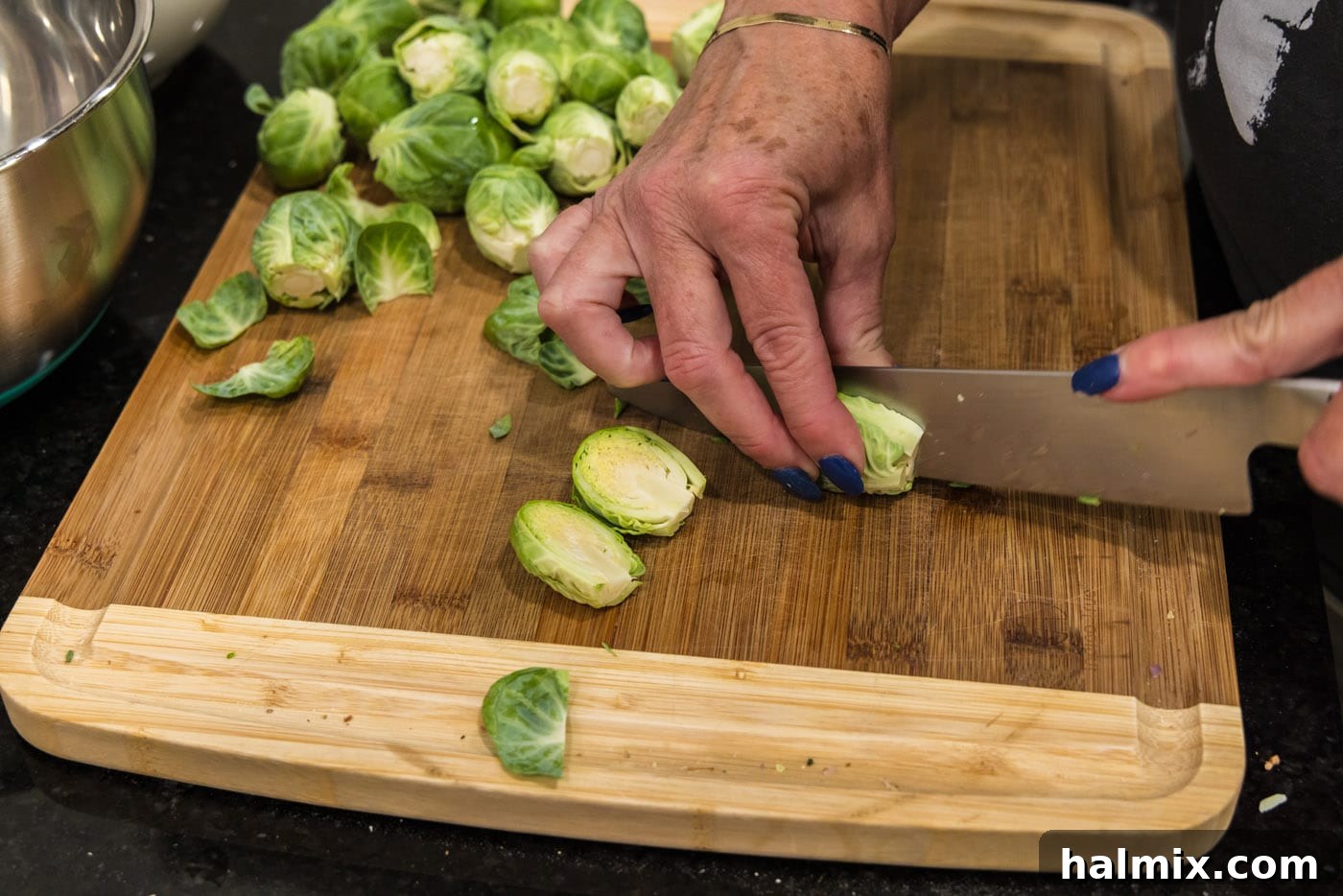 slicing brussels sprouts in half lengthwise, showing the prepared halves