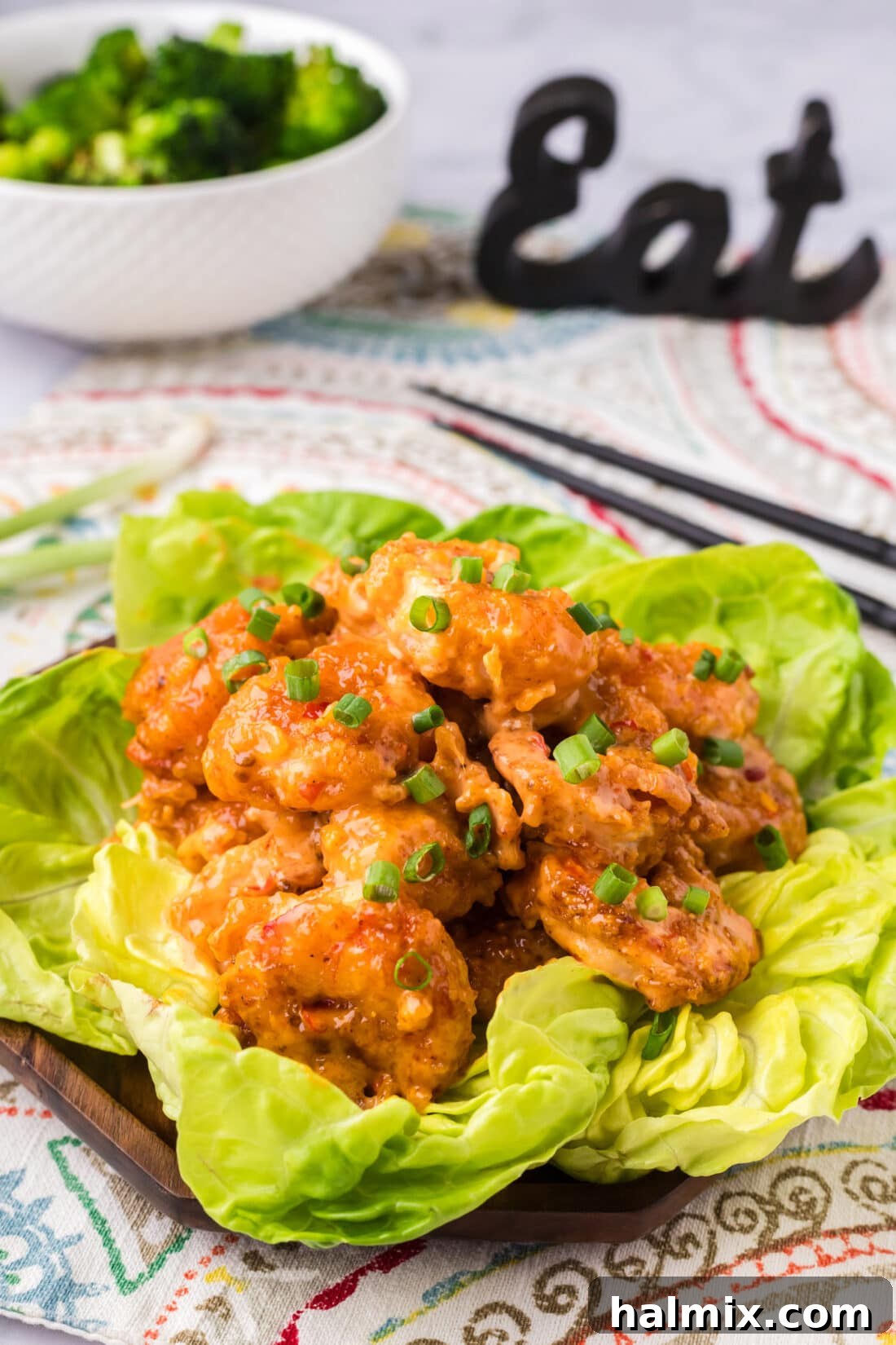 Electric Shrimp Bites 2 Bang Bang Shrimp on a bed of lettuce with a bowl of broccoli in the background