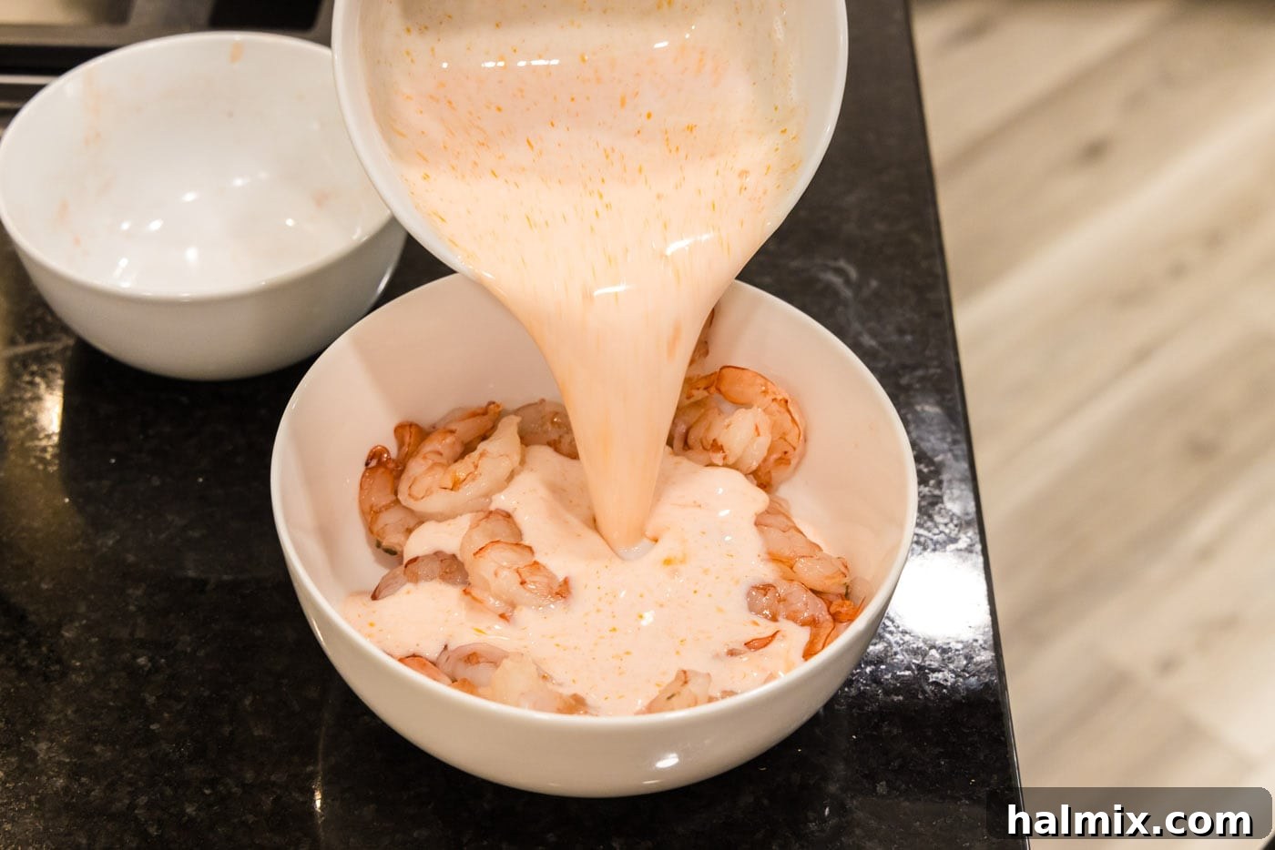 Electric Shrimp Bites 7 pouring buttermilk hot sauce mixture over shrimp in a bowl