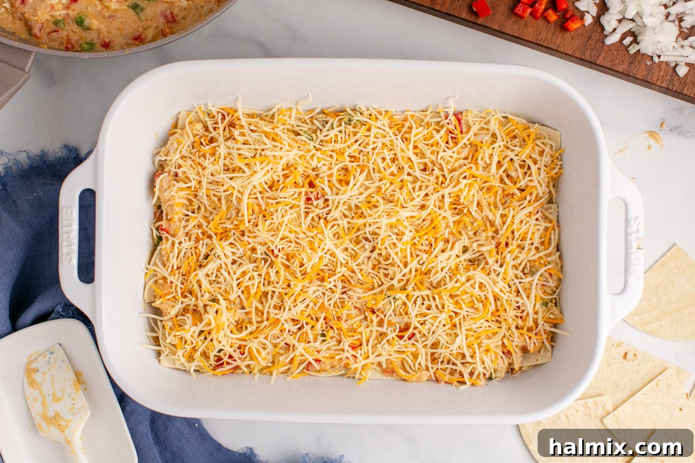 Hearty King Ranch Chicken Bake 14 Shredded cheese generously sprinkled over the chicken and sauce layer in a baking dish.