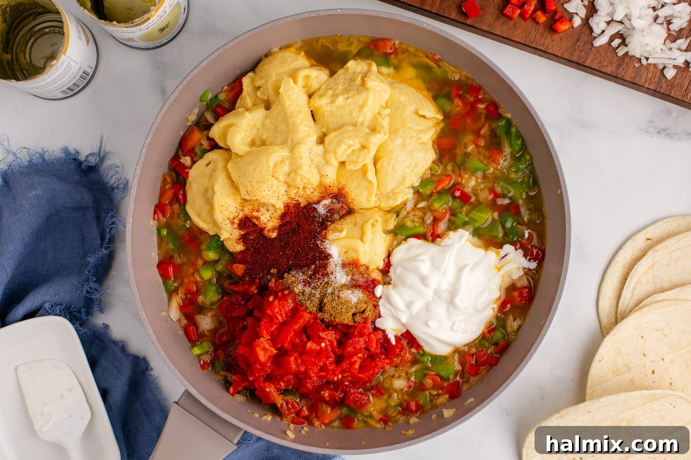Hearty King Ranch Chicken Bake 7 Cream of chicken soup, seasonings, and sour cream being added to the sautéed vegetables in a skillet.