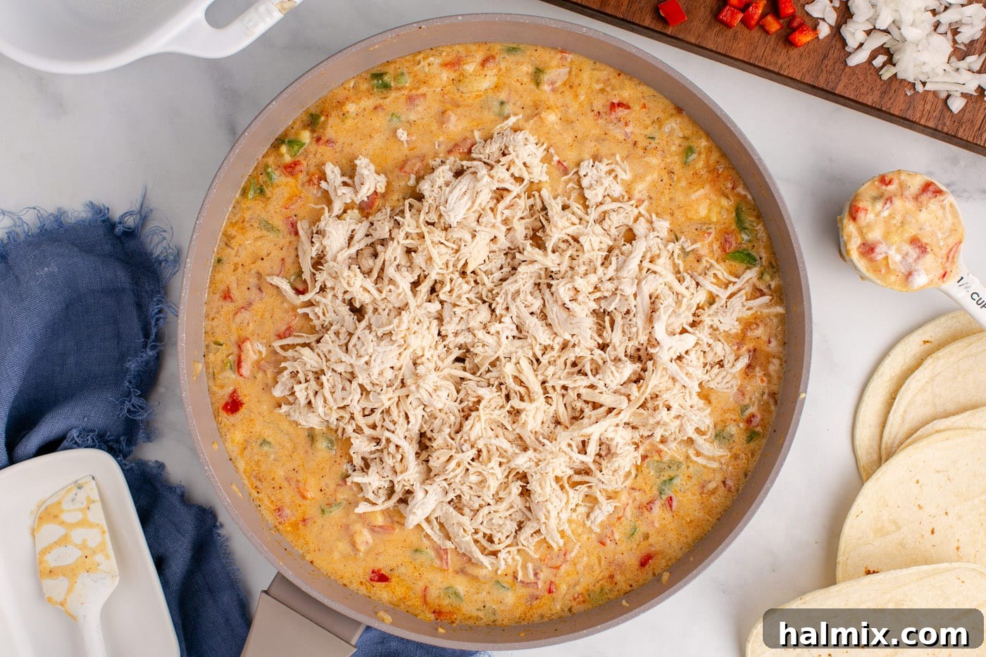 Hearty King Ranch Chicken Bake 9 Shredded chicken being stirred into the creamy sauce for King Ranch casserole.