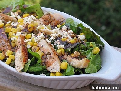 A close-up photo of a grilled chicken salad with herbed tomato vinaigrette served in a white dish.
