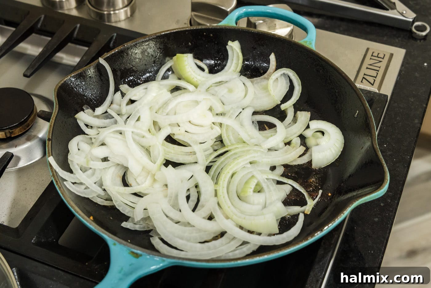 Raw sliced onion cooking in a skillet with brown bits