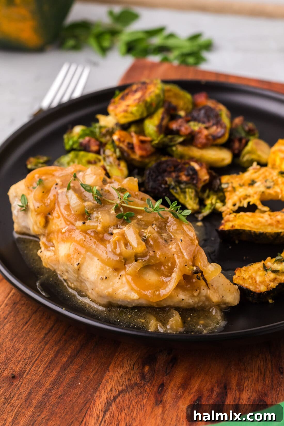 Plated Chicken with Onion Thyme Sauce alongside roasted Brussels sprouts and acorn squash, ready to be served.