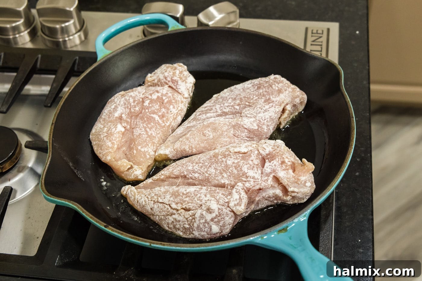 Searing flour coated chicken breasts in a hot skillet