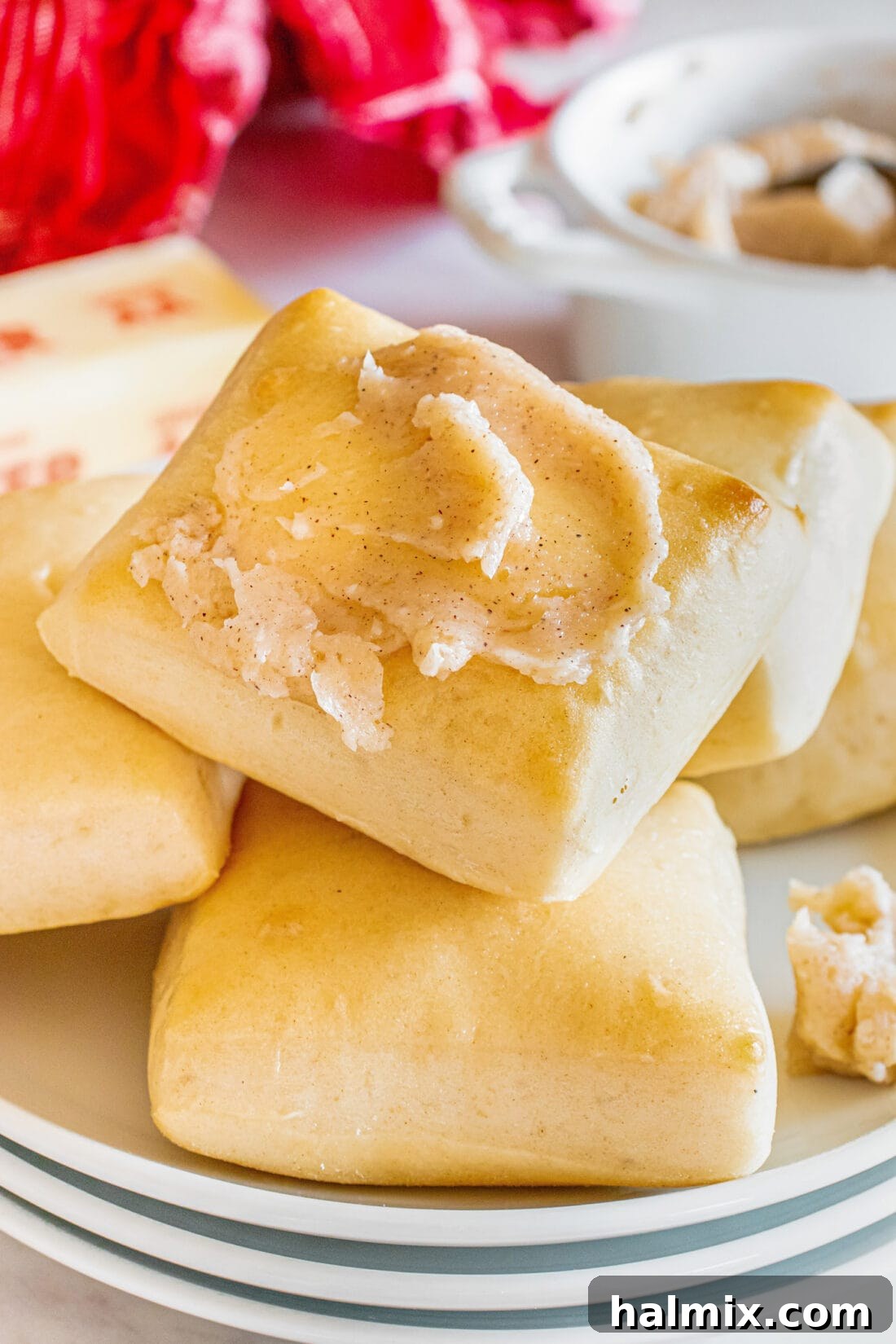 Close up photo of a Texas Roadhouse Roll topped with butter, ready to be enjoyed.