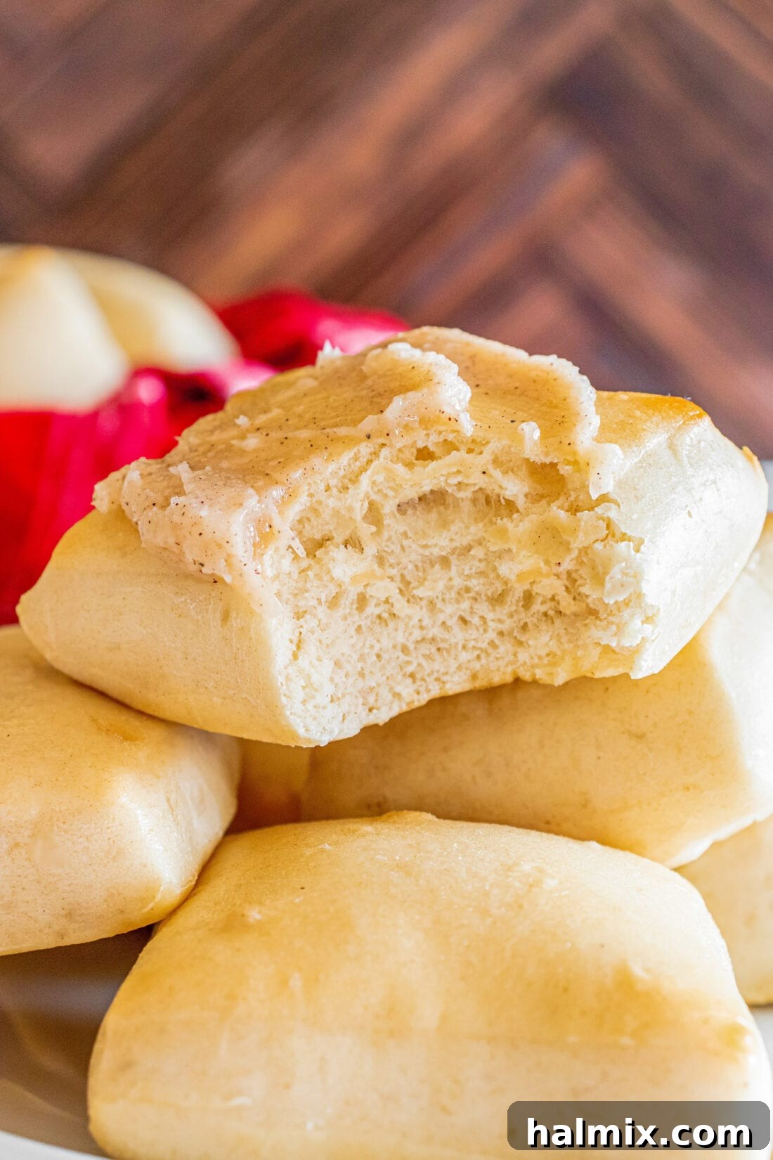 Close up photo of a Texas Roadhouse Roll topped with butter, with a small bite taken out, showing its fluffy interior.