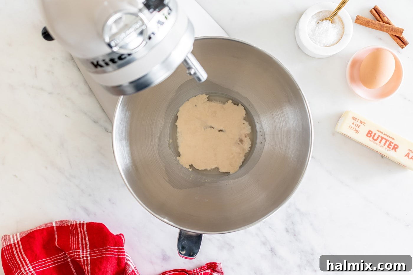 Active dry yeast, sugar, and warm water proofing in a stand mixer bowl, showing a foamy surface.
