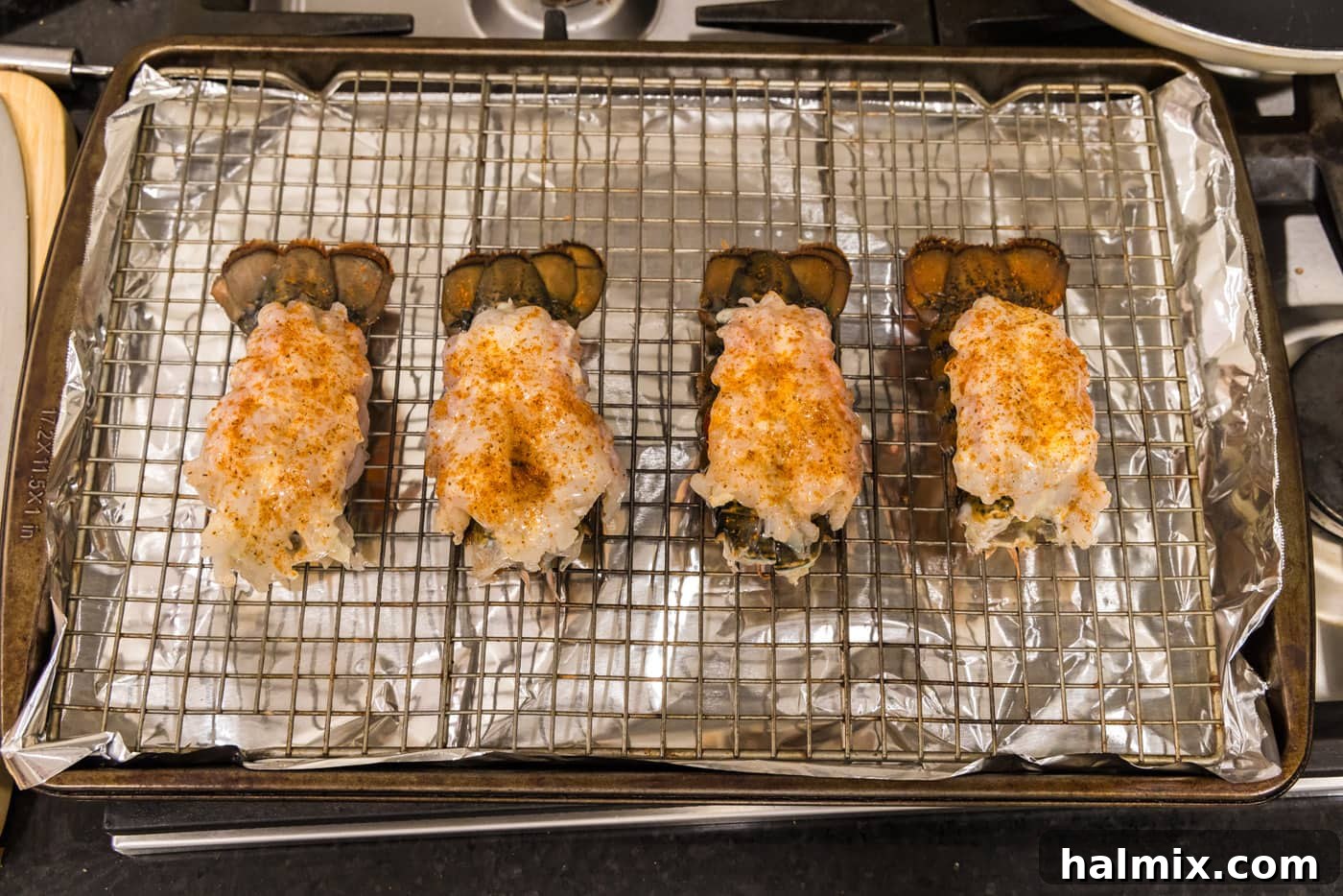 Old bay seasoned crowned lobster tails on a baking sheet