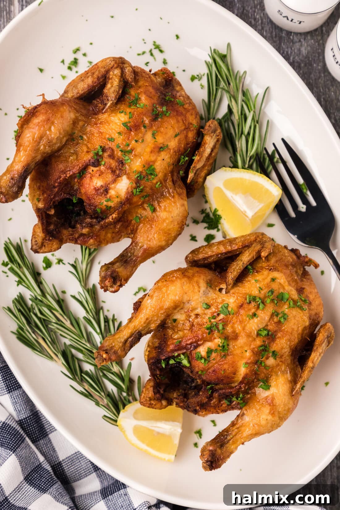 Deep Fried Cornish Hens on a platter with lemons and herbs