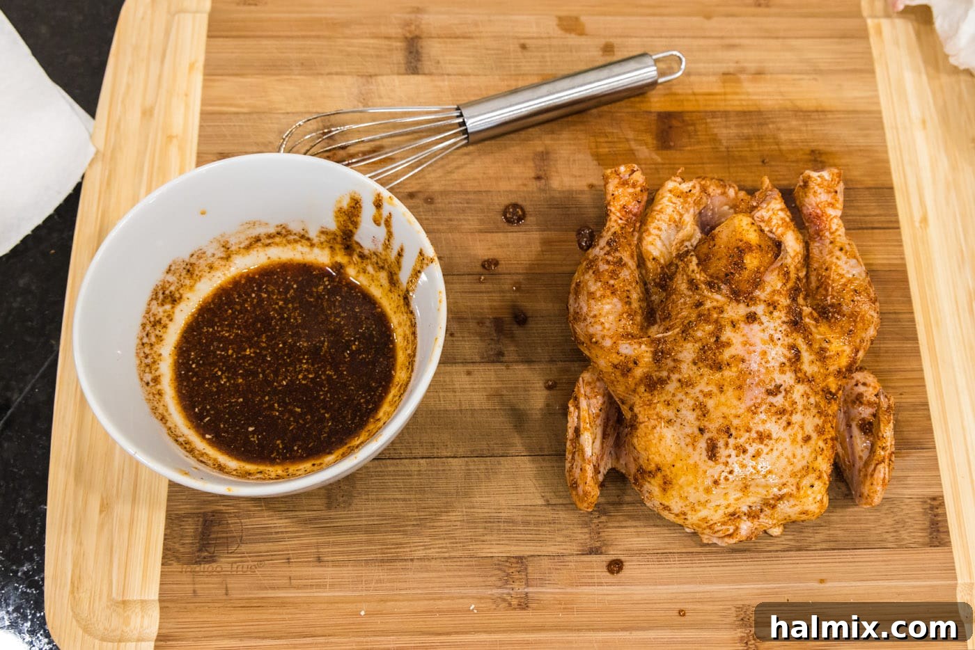 adding wet rub to cornish hen on a cutting board