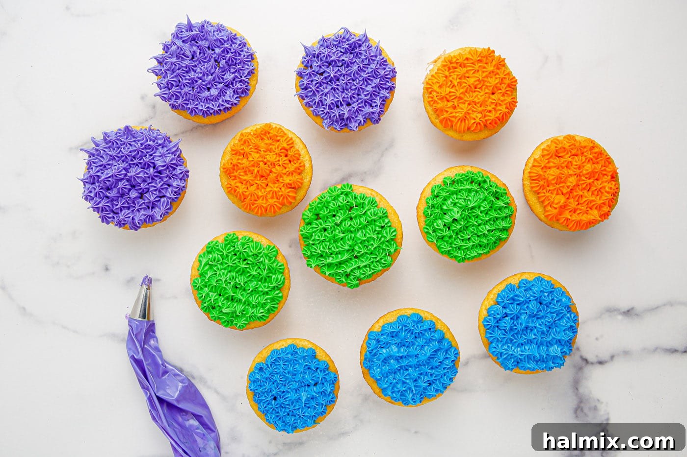 Cupcakes decorated with colorful piped frosting in various Halloween shades