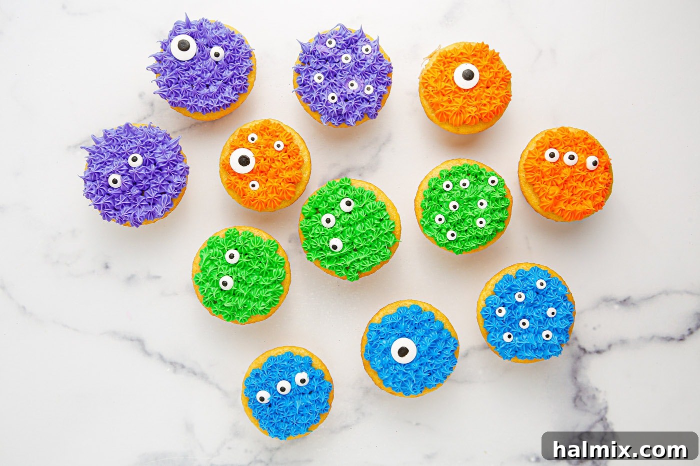 Decorating monster cupcakes by placing candy eyeballs onto the colorful frosting