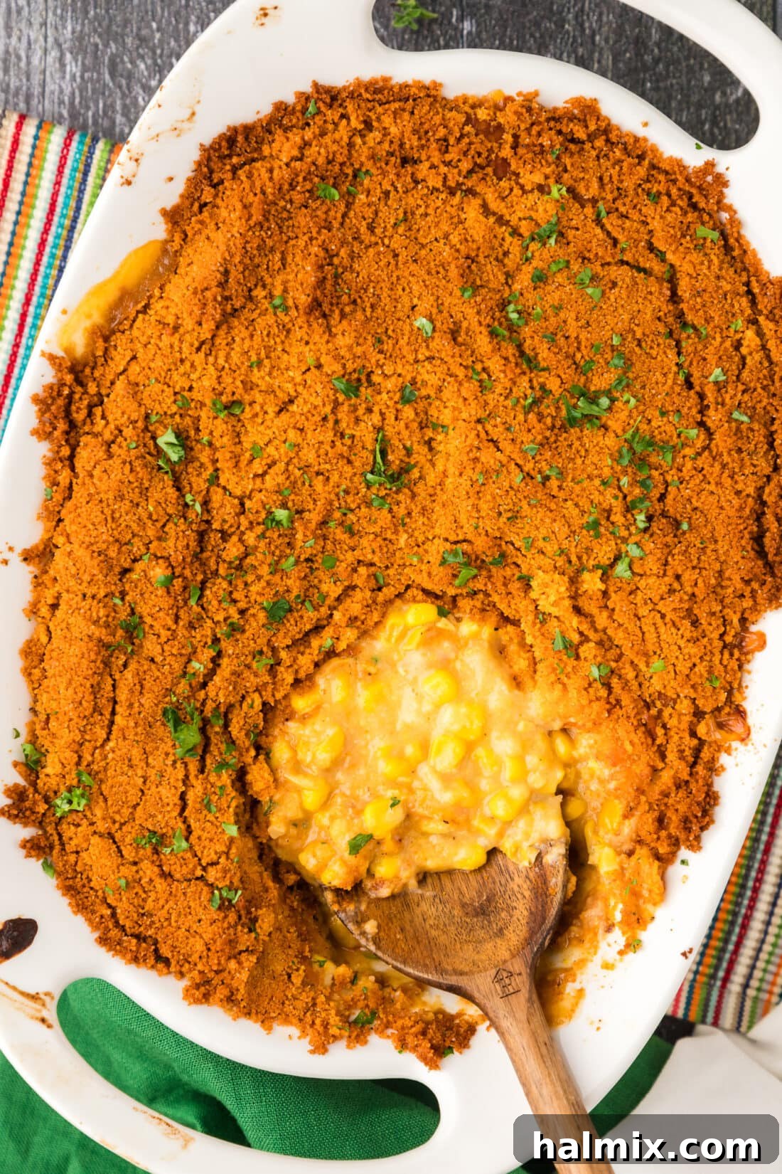 Golden Comfort Corn Bake 15 A large pan of freshly baked Scalloped Corn with a serving spoon nestled in, showing the golden-brown, crispy topping and creamy interior.