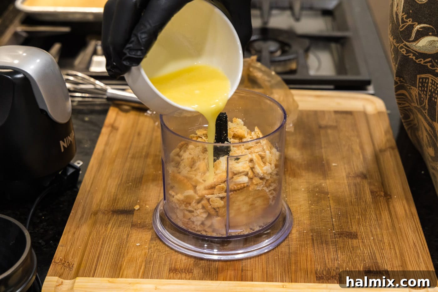 Golden Comfort Corn Bake 5 Melted butter being poured into a food processor with crushed Ritz crackers to create a buttery topping.