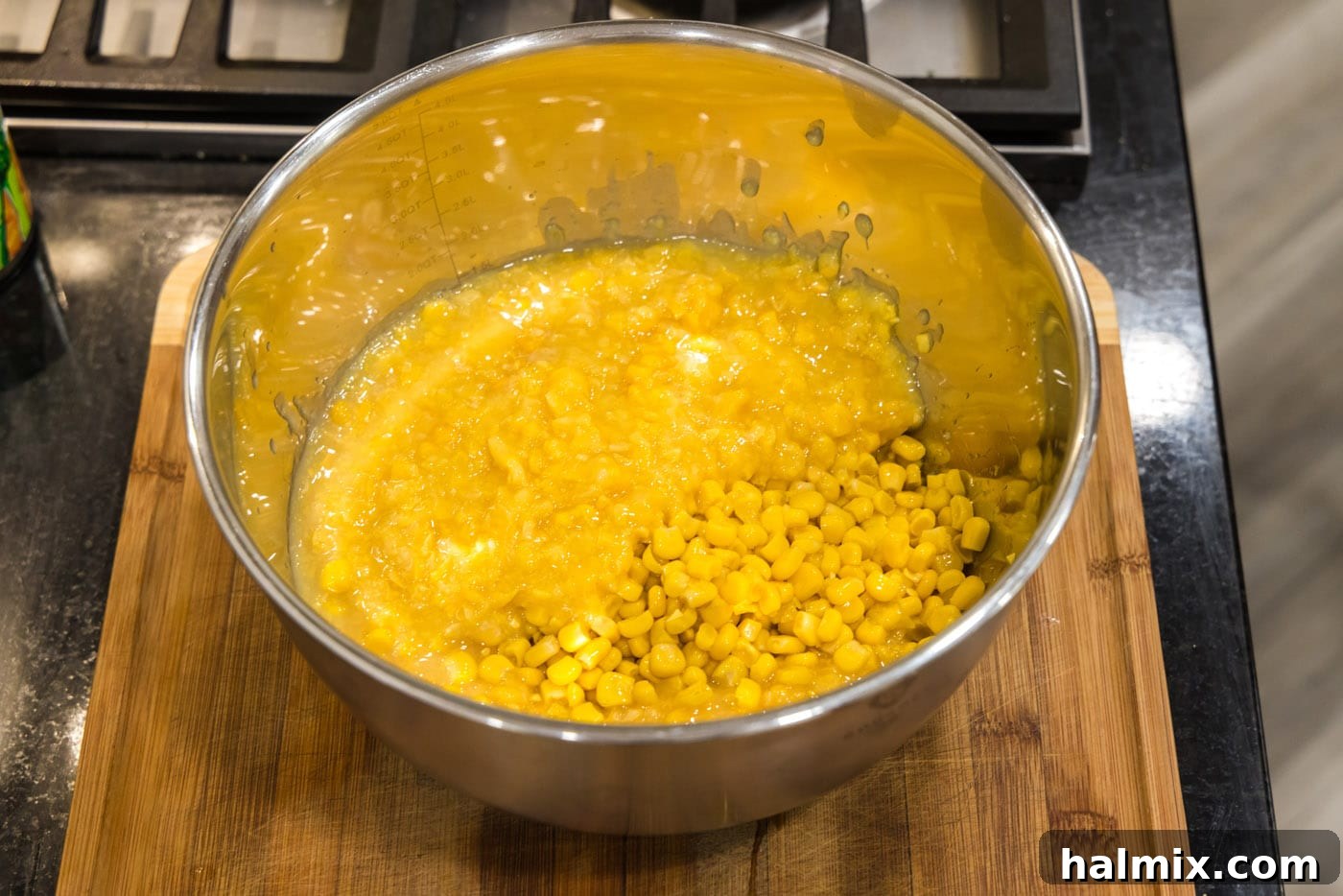 Golden Comfort Corn Bake 8 Drained whole kernel corn and creamy creamed corn in a large mixing bowl, forming the base of the casserole.