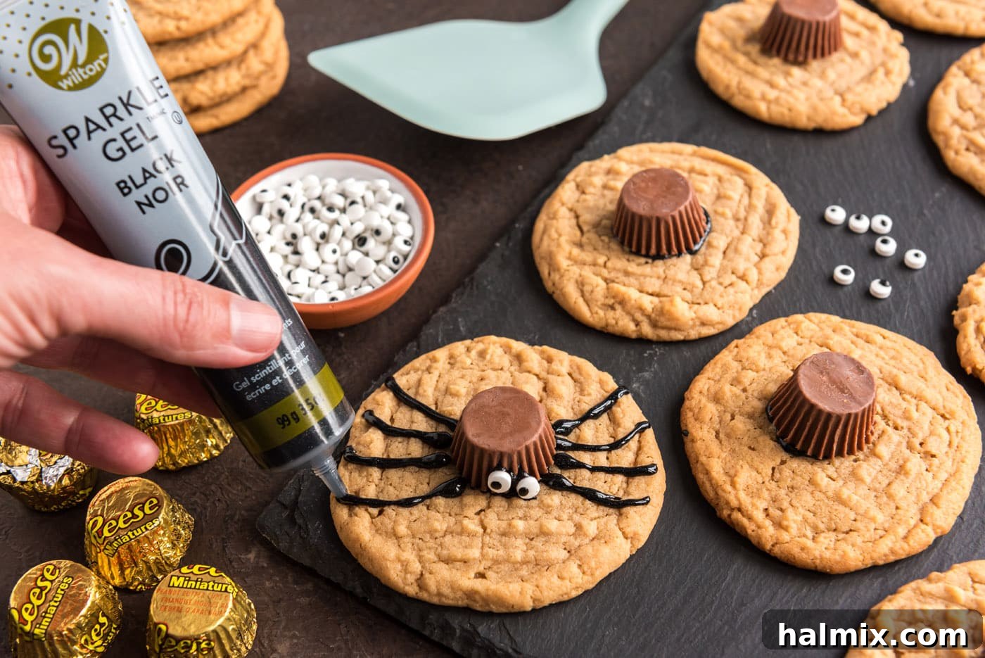 piping black decorator gel onto cookie to make spider legs