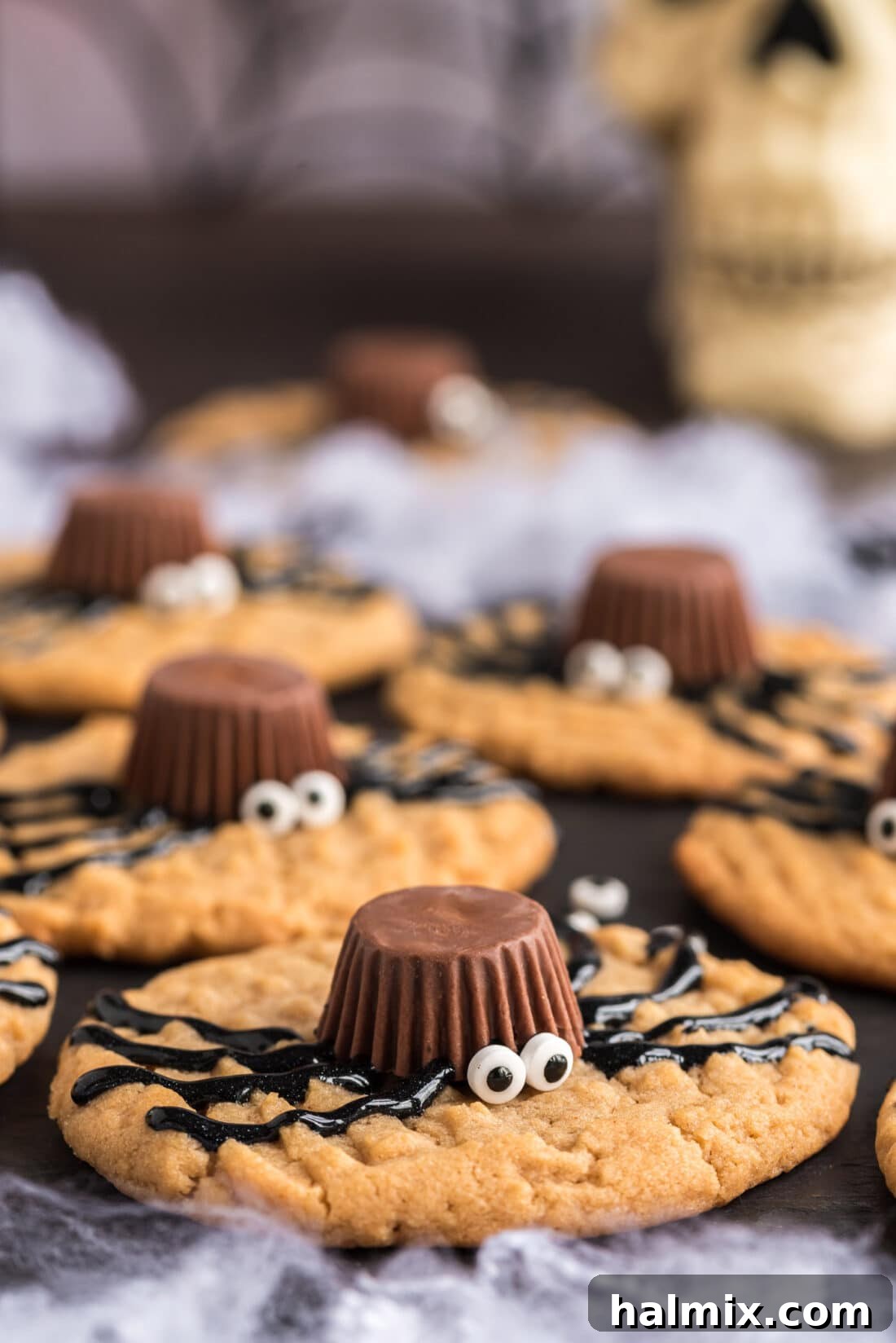 A close-up view of a selection of freshly decorated spider cookies arranged on a festive platter, highlighting their charming candy eyes and piped legs.