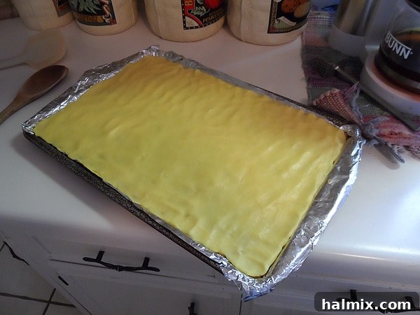 A visual of the smooth, creamy pudding mixture being spread meticulously over the crunchy cereal base layer in the lined baking pan.