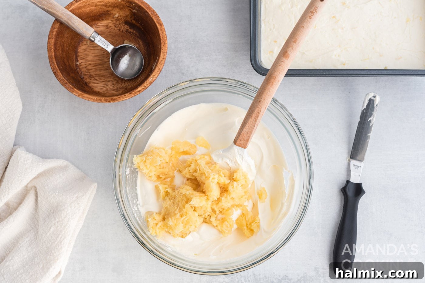 Tropical Pineapple Bliss 9 Crushed pineapple being mixed into Cool Whip with a spatula for the top layer.