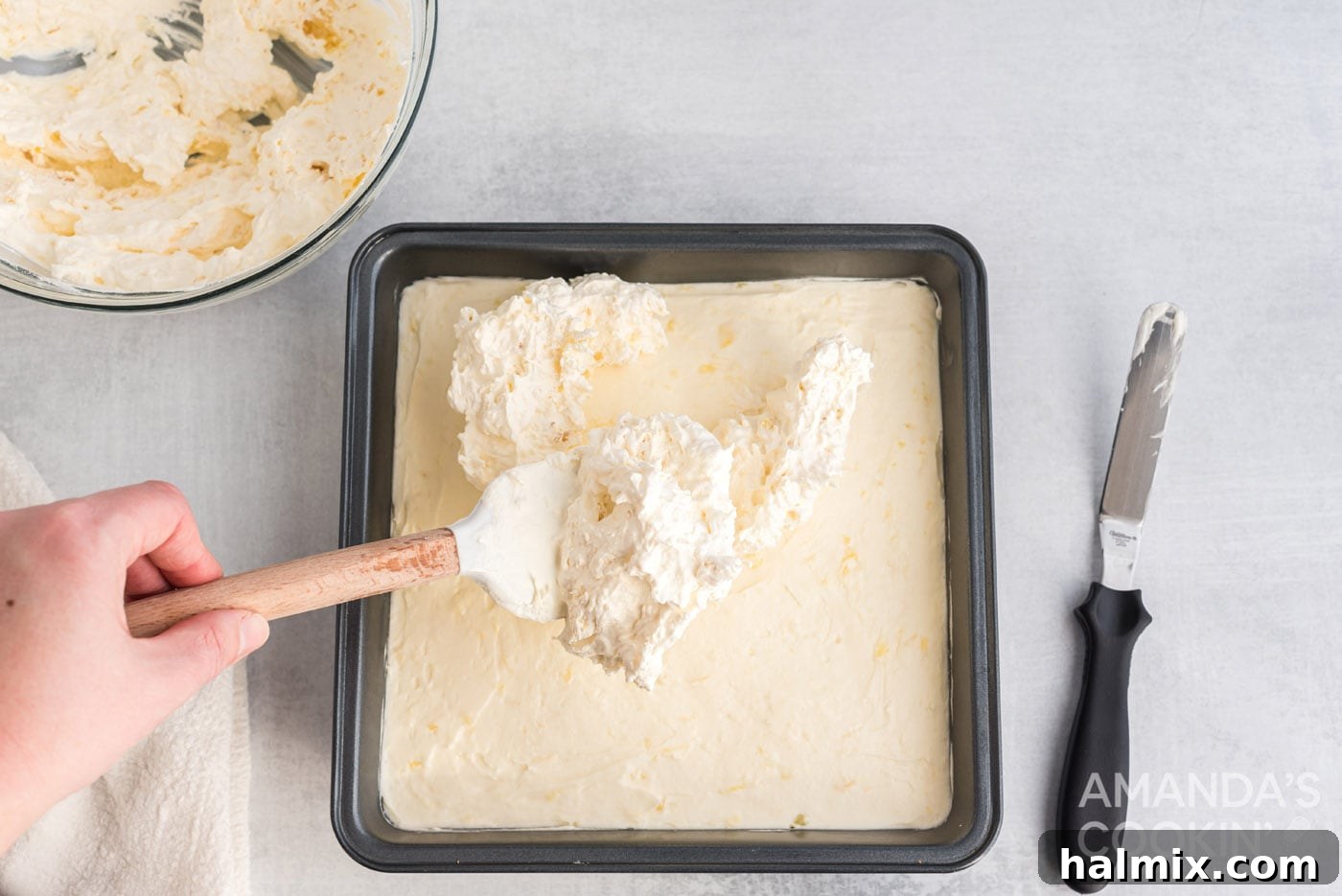 Tropical Pineapple Bliss 10 The pineapple-Cool Whip mixture being carefully spread as the top layer of the dessert.