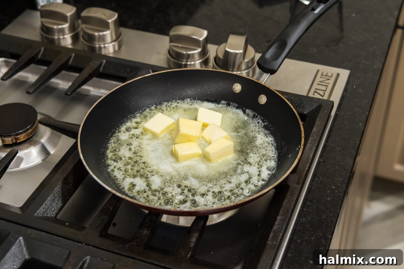Melting unsalted butter in a hot skillet, with visible foam forming on the surface.