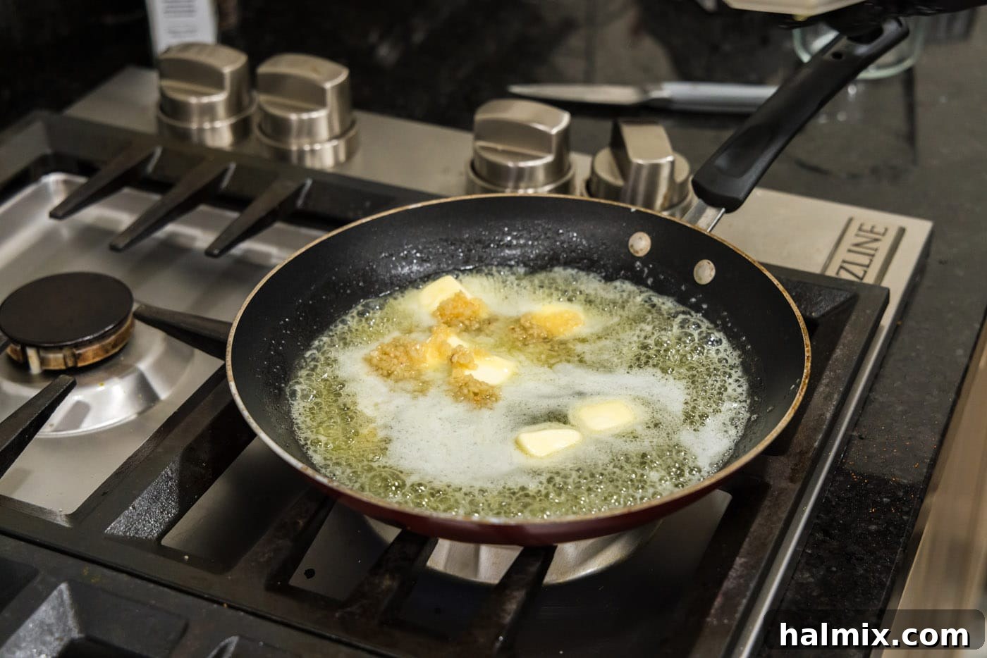 Adding minced garlic to a skillet with melted, foamy butter, preparing to infuse the flavors.