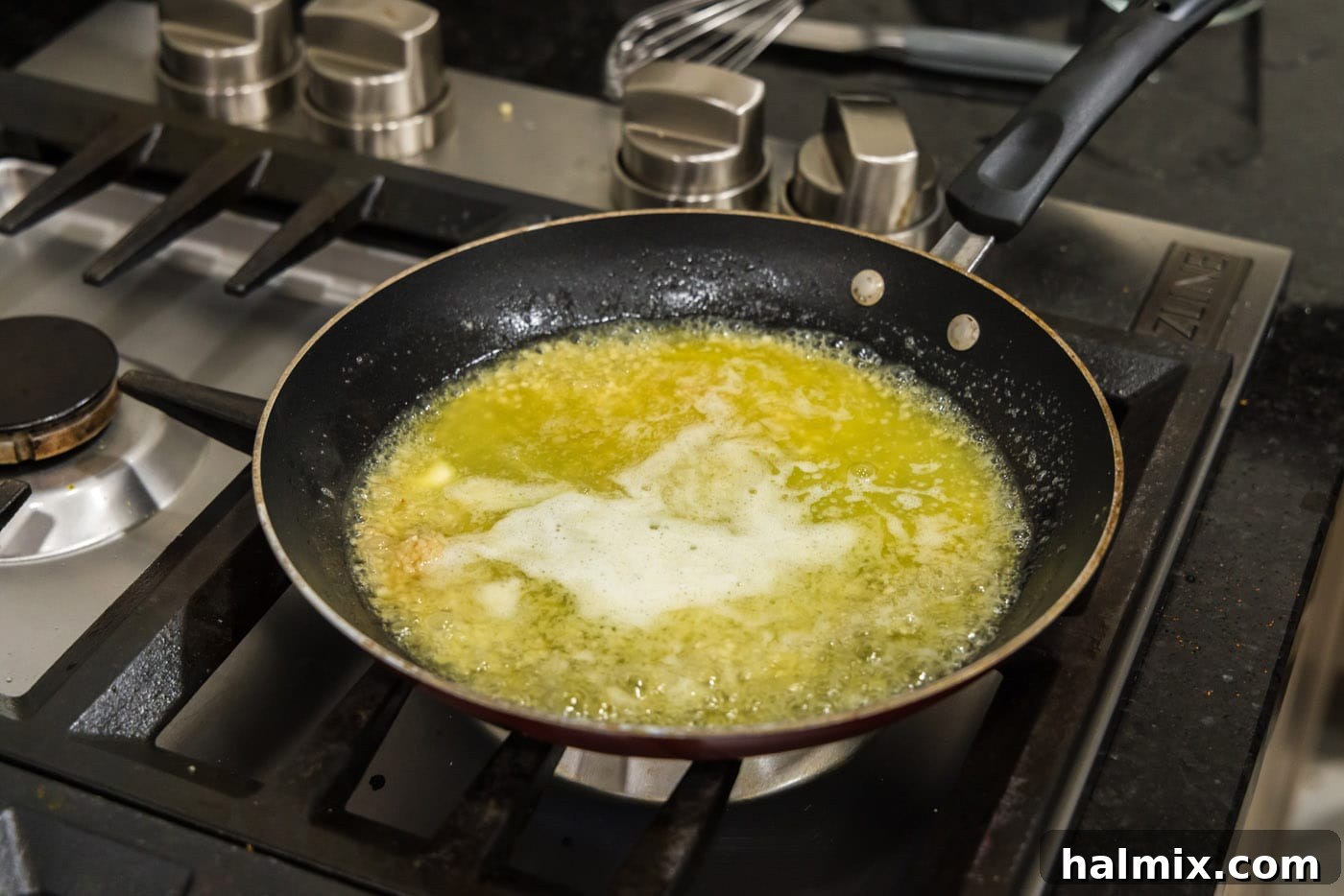 The garlic butter sauce simmering gently in a skillet after lemon juice has been added, maintaining a consistent whisk.
