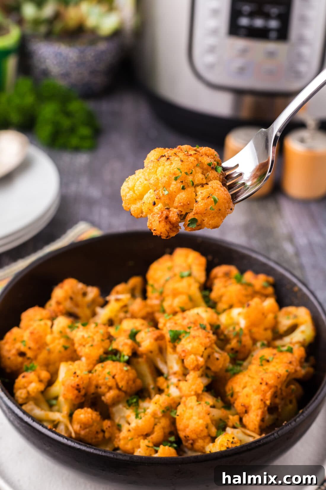 Effortless Instant Pot Cauliflower 3 A close-up of a perfectly cooked piece of Instant Pot Cauliflower on a fork, held above a bowl of the finished dish, showcasing its tender texture and appealing seasoning.
