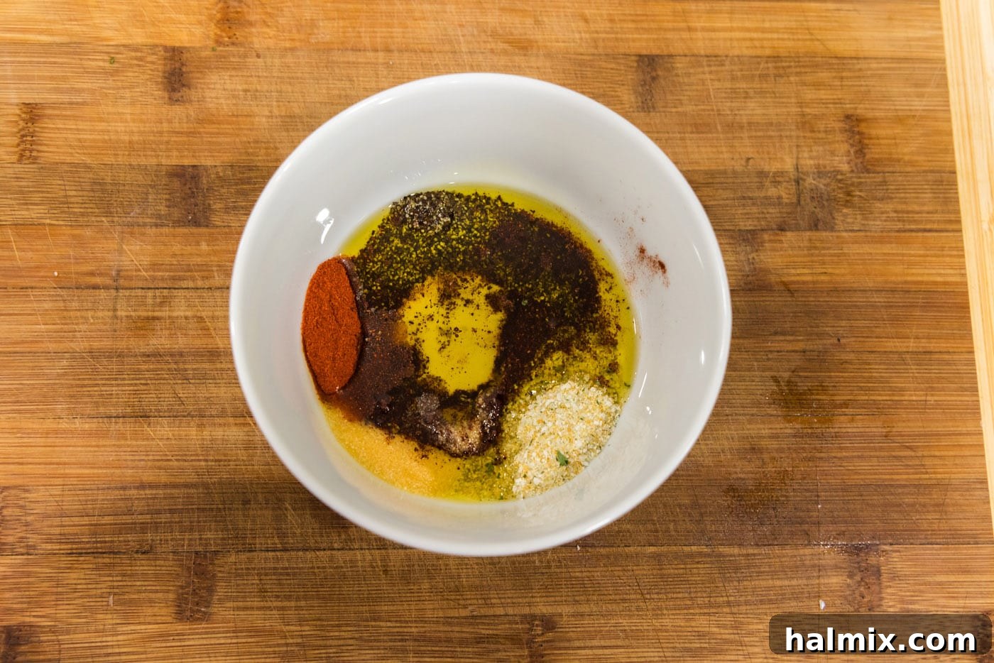 Effortless Instant Pot Cauliflower 5 A small bowl containing olive oil and various spices, mixed together to form a vibrant seasoning paste.