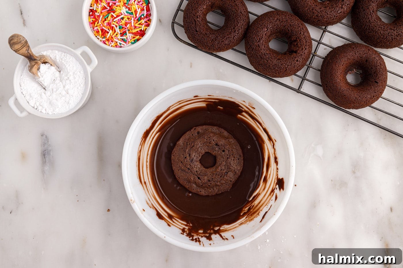 Dipping a baked donut into the rich chocolate glaze