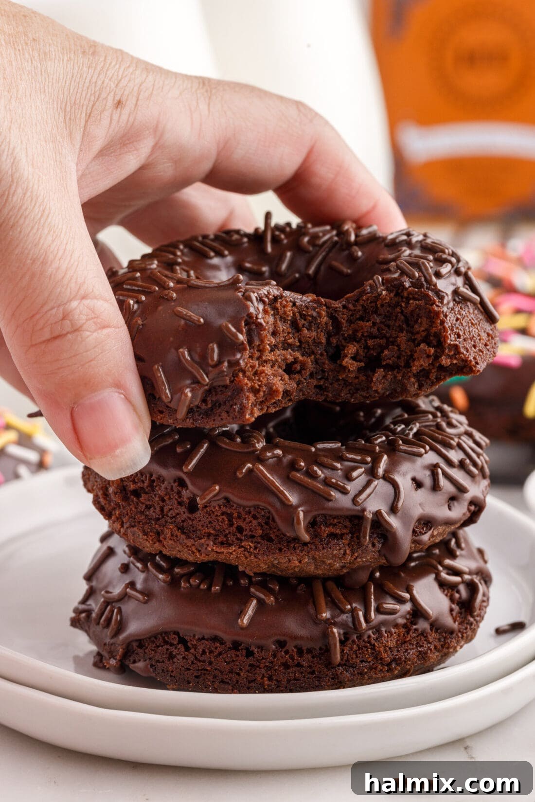 Hand placing a Bronut on a stack of Bronuts, highlighting its texture and decoration