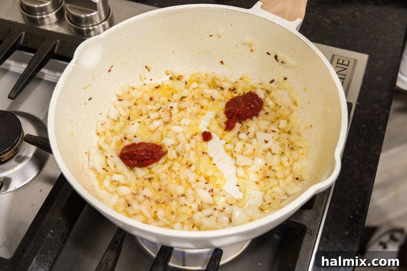 tomato pasta added to skillet of onion mixture