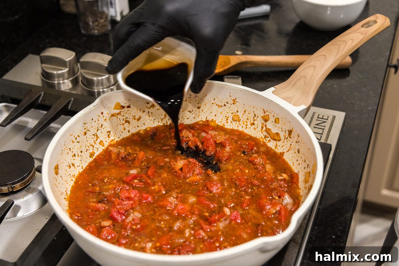 pouring balsamic vinegar into skillet with vodka sauce