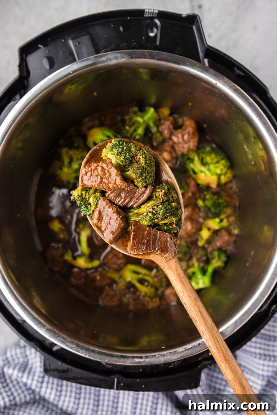Spoon of Instant Pot Beef and Broccoli held above an instant pot
