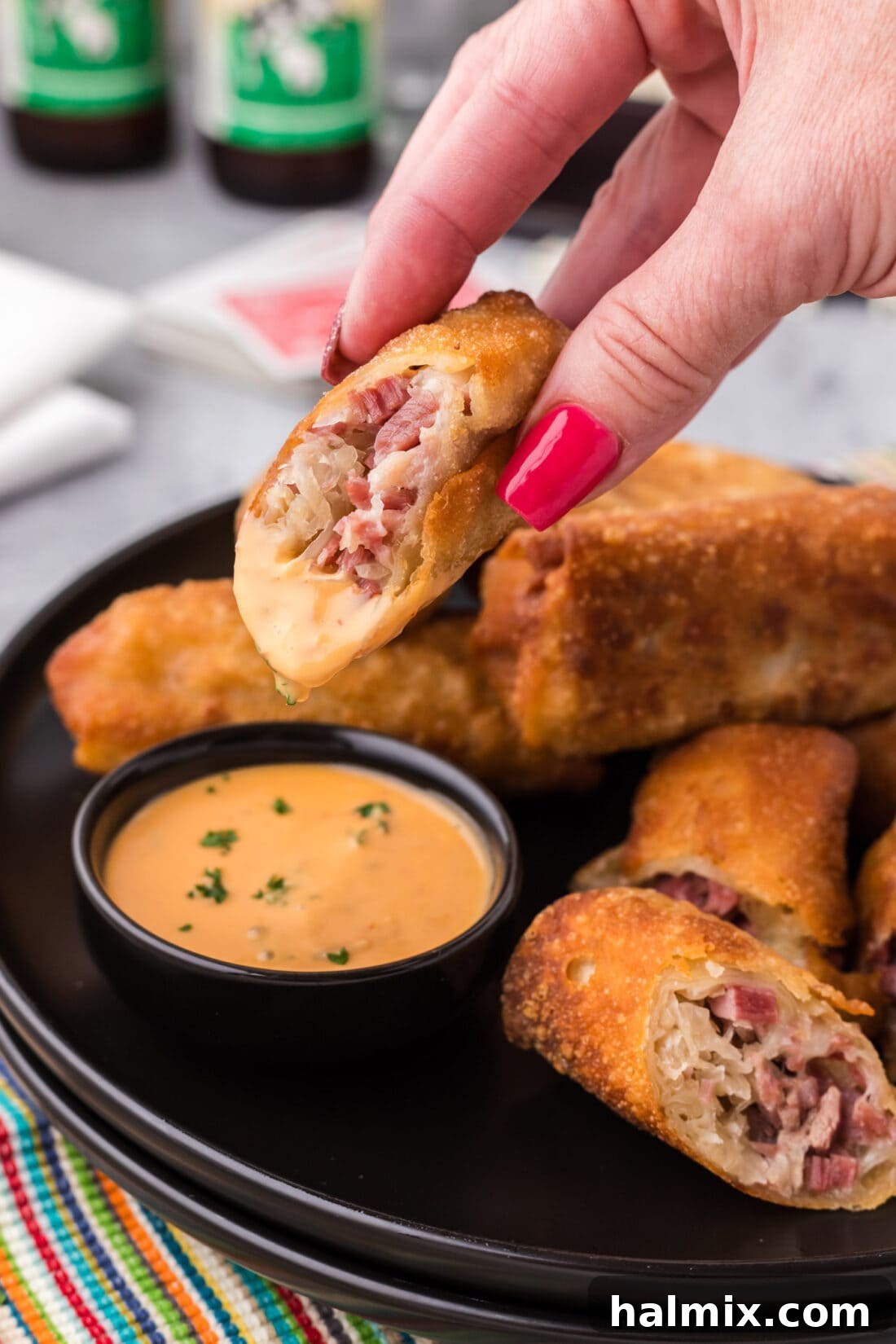 Crispy Reuben Egg Rolls 3 Half of a crispy Reuben Egg Roll dipped into a bowl of creamy thousand island dressing, showing the melted cheese and filling.